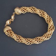 This Monet bracelet from the 80's is twisted gold tone metal with a braided chain.  Excellent condition with a fold-over clasp. Vintage Metal Bracelets With Gold Chain, Vintage Gold Chain Metal Bracelet, Vintage Gold Braided Bracelets As Gift, Gold Metal Bangle Braided Bracelet, Gold Metal Braided Bracelet, Gold Metal Braided Bangle Bracelet, Gold-tone Box Chain Link Gold Bracelet, Vintage Gold-tone Chain Bracelets, Gold-tone Brass Chain Link Bracelet