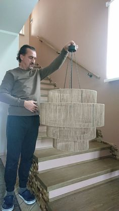 a man standing on some stairs holding a chandelier