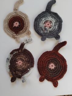 four crocheted coasters sitting on top of a white table next to each other