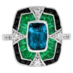 A striking and intriguing jewel, indeed. This bold and colorful Art Deco style ring highlights a gorgeous gleaming emerald cut London blue topaz framed in eye-catching contrast by French cut emerald and black onyx. Each side and shoulders set off with round diamond with milgrain edge. Ring Information Style: Edwardian Metal: 18K White Gold Weight: 6.50 g. (approx. total weight) Ring Size: US3-8 Center Gemstone Type: London Blue Topaz Shape: Octagon Size: 8 x 5.5 mm. Number: 1 Weight: 2.00 Carat Vintage Emerald Rings Blue Nile, Luxury Enamel Art Deco Rings, Luxury Blue Art Deco Rings, Gem Rings Stones 1stdibs, Edwardian Onyx Rings, Luxury Emerald Gemstones With Accent Stones, Luxury Sapphire Ring With Emerald Cut And Gemstone Accents, Luxury Emerald-cut Sapphire Ring With Gemstone Accents, Luxury Emerald Cut Sapphire Ring With Gemstone Accents