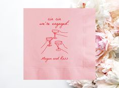 a pink napkin with the words, can we be engaged? on it next to flowers