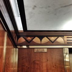 the door to an elevator is decorated with wood and metal accents, along with a sign that reads ous