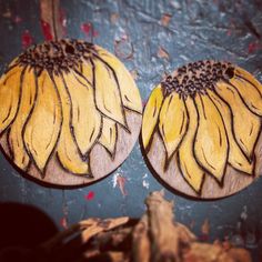 two sunflowers are painted on wooden discs