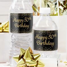 two water bottles with happy 50th on them and a gold bow next to each other