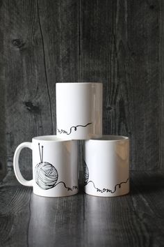 three coffee mugs sitting on top of each other with yarn and knitting needles drawn on them