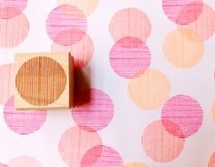 a wooden stamp sitting on top of a pink and yellow wallpaper covered in circles