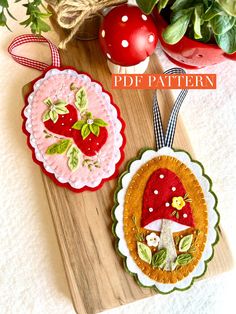 two handmade christmas ornaments sitting on top of a wooden cutting board