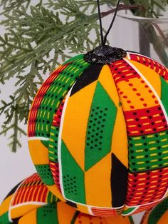 an ornament hanging from a christmas tree with green and red designs on it