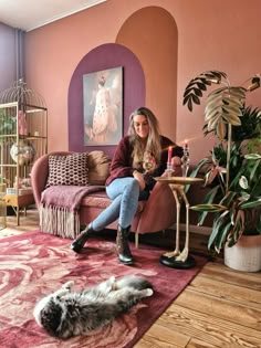 a woman sitting on a couch next to a cat and a table with a candle in it