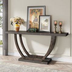 a console table with flowers, candles and pictures on it