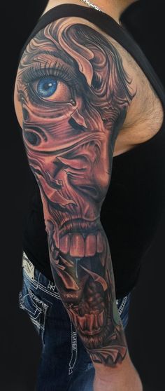 a man's arm with an evil face and blue eyes on the left sleeve