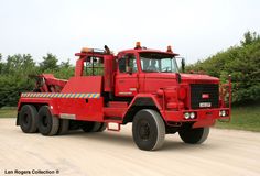 a large red truck parked on top of a dirt road