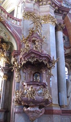 an ornate clock in the middle of a building with gold decorations on it's sides