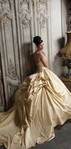 a woman in a ball gown leaning against a wall