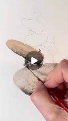 someone is drawing something on top of some rocks with a pencil and watercolor pen