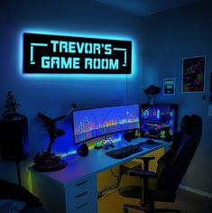 a gaming room with neon lights and a computer on a desk in front of the game room sign