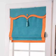 a blue and orange roman blind with tassels on it in front of a window