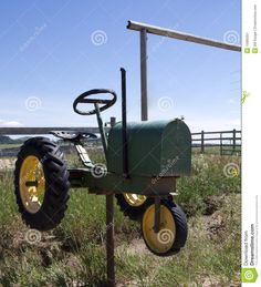 an old farm tractor is attached to a pole in the grass by a fence on a sunny day