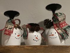 three snowmen with hats and scarves on their heads are sitting in a row