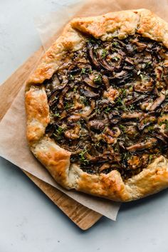 a pizza with mushrooms on it sitting on top of a wooden cutting board