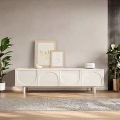 a living room with potted plants on the floor and a white tv stand in front of it