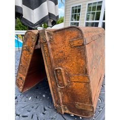 an old suitcase sitting on top of a metal table next to a pool and house