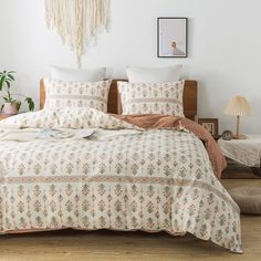 a bed with white and orange comforters in a bedroom next to a plant on the floor