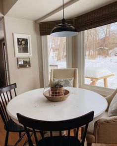 a dining room table with a basket on top of it in front of a window