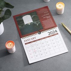 a desk calendar with candles and a pen on it