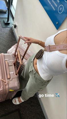 a woman standing next to a pink piece of luggage with her hand on the handle