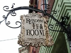 a sign hanging from the side of a building that says random tea room on it