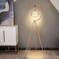 a floor lamp with a white shade on it in a room next to a painting