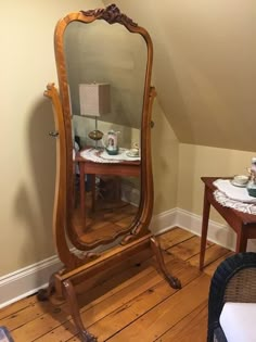 a large mirror sitting on top of a wooden floor next to a table and chair