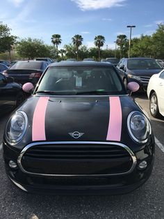 a black mini with pink stripes parked in a parking lot