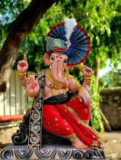 an elephant statue sitting on top of a table in front of a tree and fence