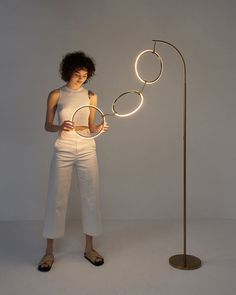 a woman standing next to a lamp that has circles on it and lights up the floor