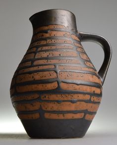 a brown and black vase sitting on top of a table