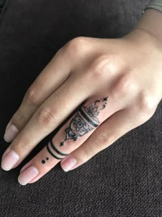 a woman's hand with a ring tattoo on her left thumb and an intricate design on the middle finger