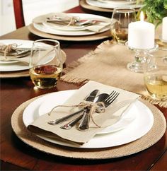 a table set with place settings and wine glasses on top of the plates, along with napkins