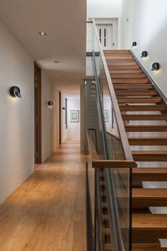 an empty hallway with wooden stairs and glass balconies on both sides, leading to the second floor