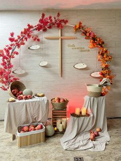 an altar with candles, apples and flowers around it in front of a cross on the wall