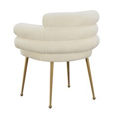 an upholstered white chair with gold legs