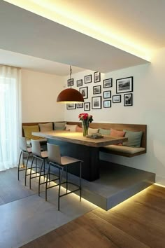 a dining room table with chairs and pictures on the wall above it, along with bar stools