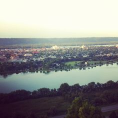 an aerial view of a city and the river in the foreground with trees on both sides