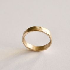 a gold wedding ring sitting on top of a white surface with no one around it