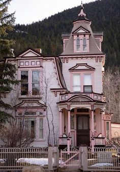 a large pink house sitting on the side of a road in front of a mountain