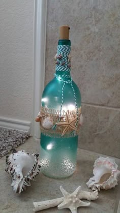 a bottle filled with sea shells sitting on top of a counter next to a starfish