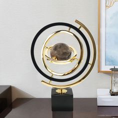 a gold and black sculpture sitting on top of a desk next to a framed painting