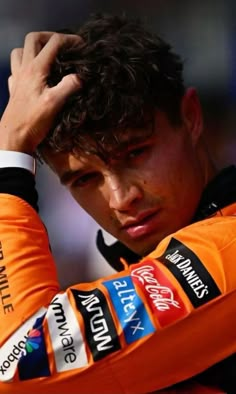 a close up of a person wearing an orange jersey and holding his hands to his head