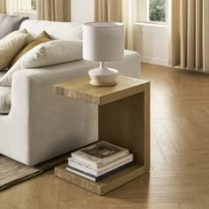 a white couch sitting next to a table on top of a hard wood floored floor